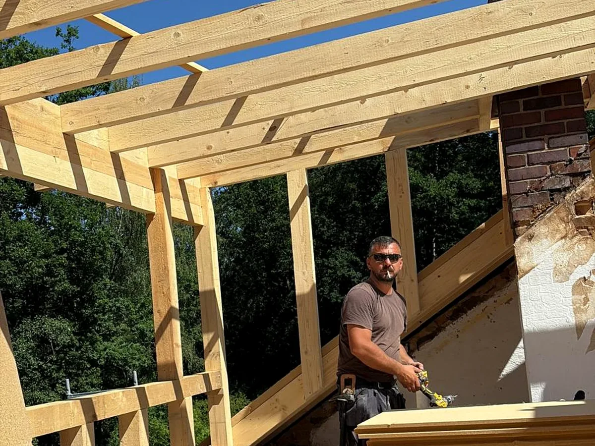 Fachkraft im neuen Holzaufbau einer Dachkonstruktion.